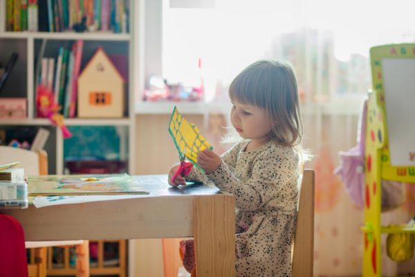 A young child in kindergarten cutting paper.