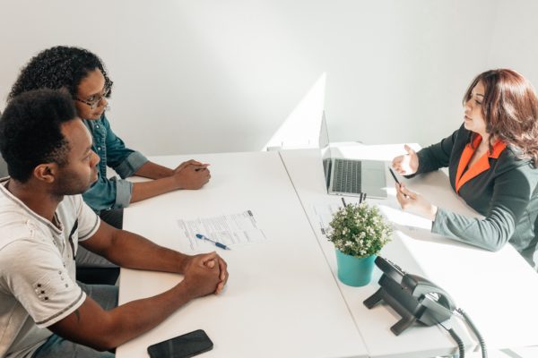 A social worker behind her computer, talking to a couple.