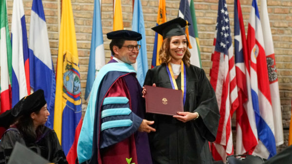 A student graduating from Saint Augustine College, standing alongside the President of SAC.